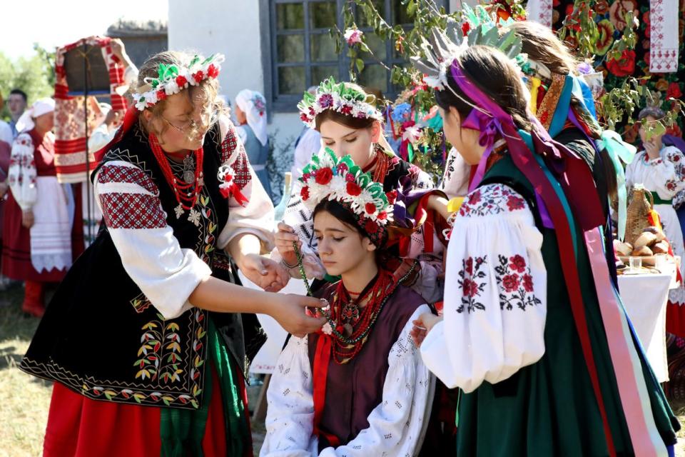 Young women in traditional costumes surround the bride as they perform a ritual during the re-enactment of a folk marriage ceremony as part of the Wedding Autumn event at the National Museum of Folk Architecture and Life in Pyrohiv, Kyiv Oblast, Ukraine on Sep. 10, 2023. (Volodymyr Tarasov / Ukrinform/Future Publishing via Getty Images)