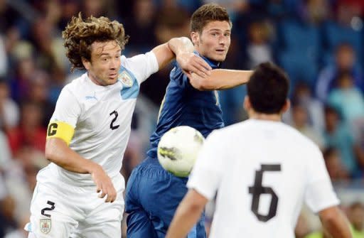 French forward Olivier Giroud (C) clashes with Uruguayan defender Diego Lugano (L) during the friendly football match at the Oceane stadium in Le Havre, western France. The match ended in a 0-0 draw