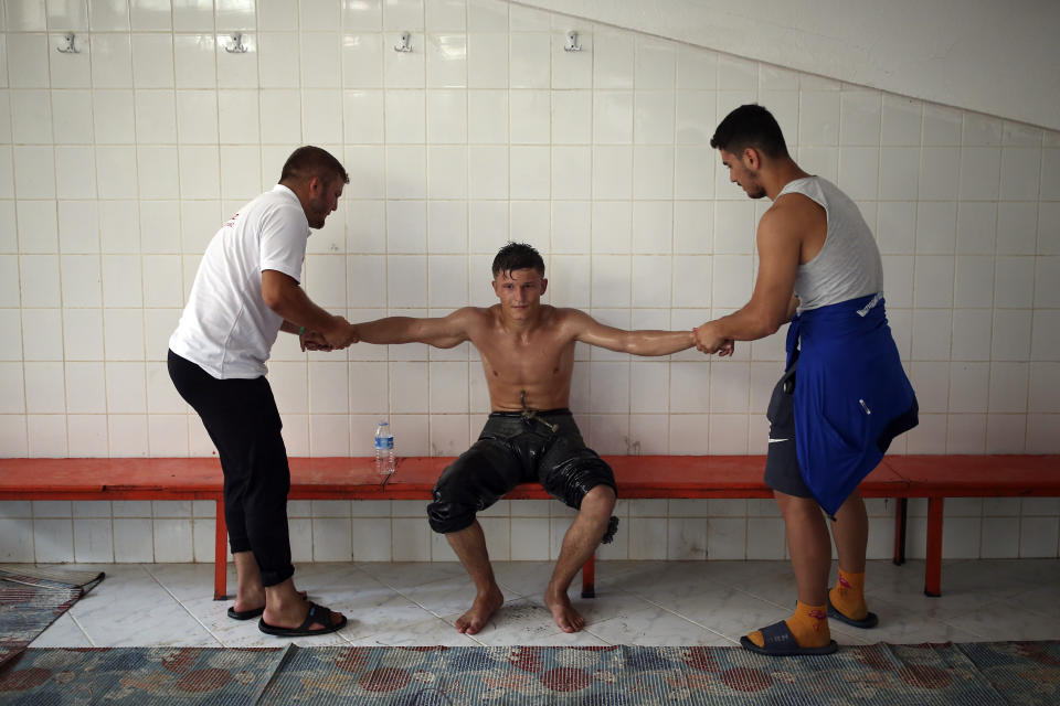 Helped by members of his team, a wrestler tries to recover following the last day of the 660th instalment of the annual Historic Kirkpinar Oil Wrestling championship, in Edirne, northwestern Turkey, Sunday, July 11, 2021.Thousands of Turkish wrestling fans flocked to the country's Greek border province to watch the championship of the sport that dates to the 14th century, after last year's contest was cancelled due to the coronavirus pandemic. The festival, one of the world's oldest wrestling events, was listed as an intangible cultural heritage event by UNESCO in 2010. (AP Photo/Emrah Gurel)