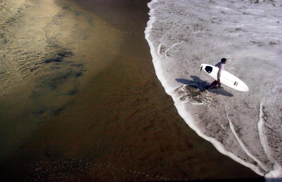 A surfer heads into the water on the Outer Banks near Rodanthe.