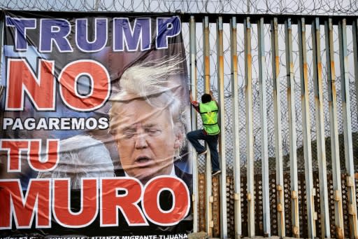 A protestor against the wall on the US-Mexico frontier hangs a banner reading "Trump we will not pay for your wall" at Playas de Tijuana, Mexico, on February 2, 2020