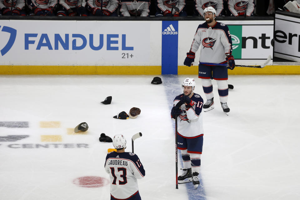 Hats litter the ice as Columbus Blue Jackets players Johnny Gaudreau (13), Justin Danforth (17) and Ivan Provorov (9) look on after Boston Bruins player Brad Marchand scored his third goal of an NHL hockey game for a hat trick during the third period Sunday, Dec. 3, 2023, in Boston. (AP Photo/Mary Schwalm)