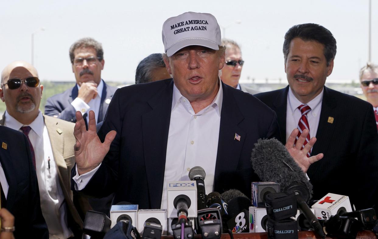 Republican presidential candidate Donald Trump gestures during a news conference near the U.S.-Mexico border (background), outside of Laredo, Texas July 23, 2015. At right is Pete Saenz, mayor of Laredo. (Photo: Rick Wilking/Reuters)