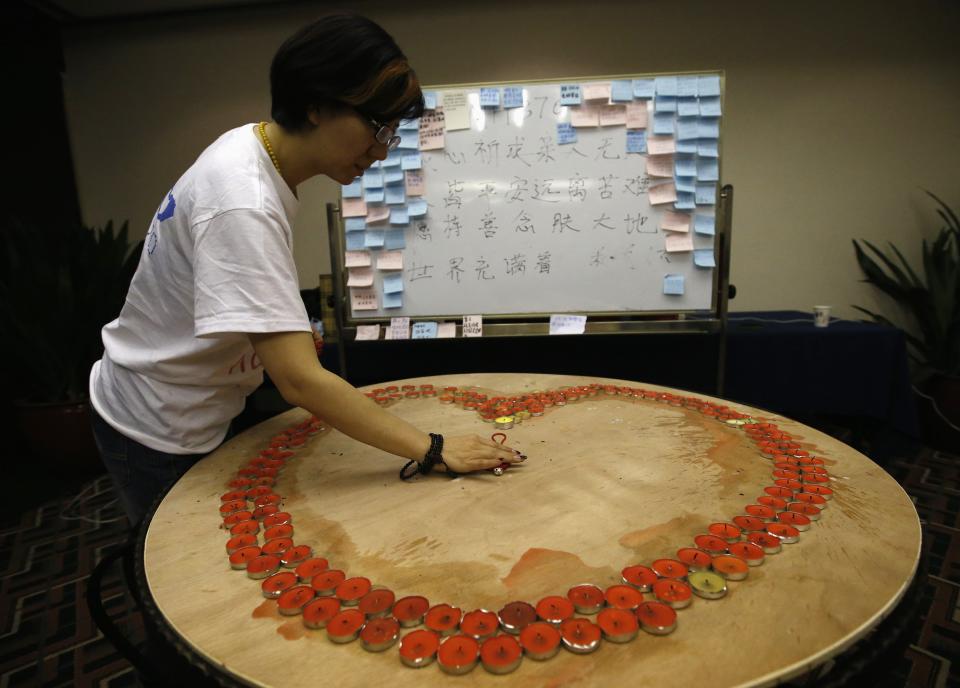 A relative of a passenger aboard Malaysia Airlines flight MH370 puts a decoration inside a ring of candles to wish for the return of the passengers at the Lido Hotel in Beijing