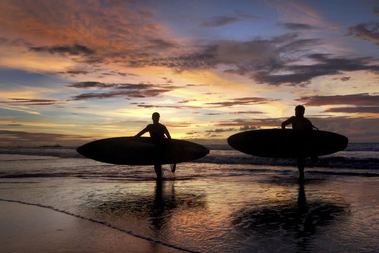 Dos surfers en el atardecer de Kuta Beach en Bali, Indonesia