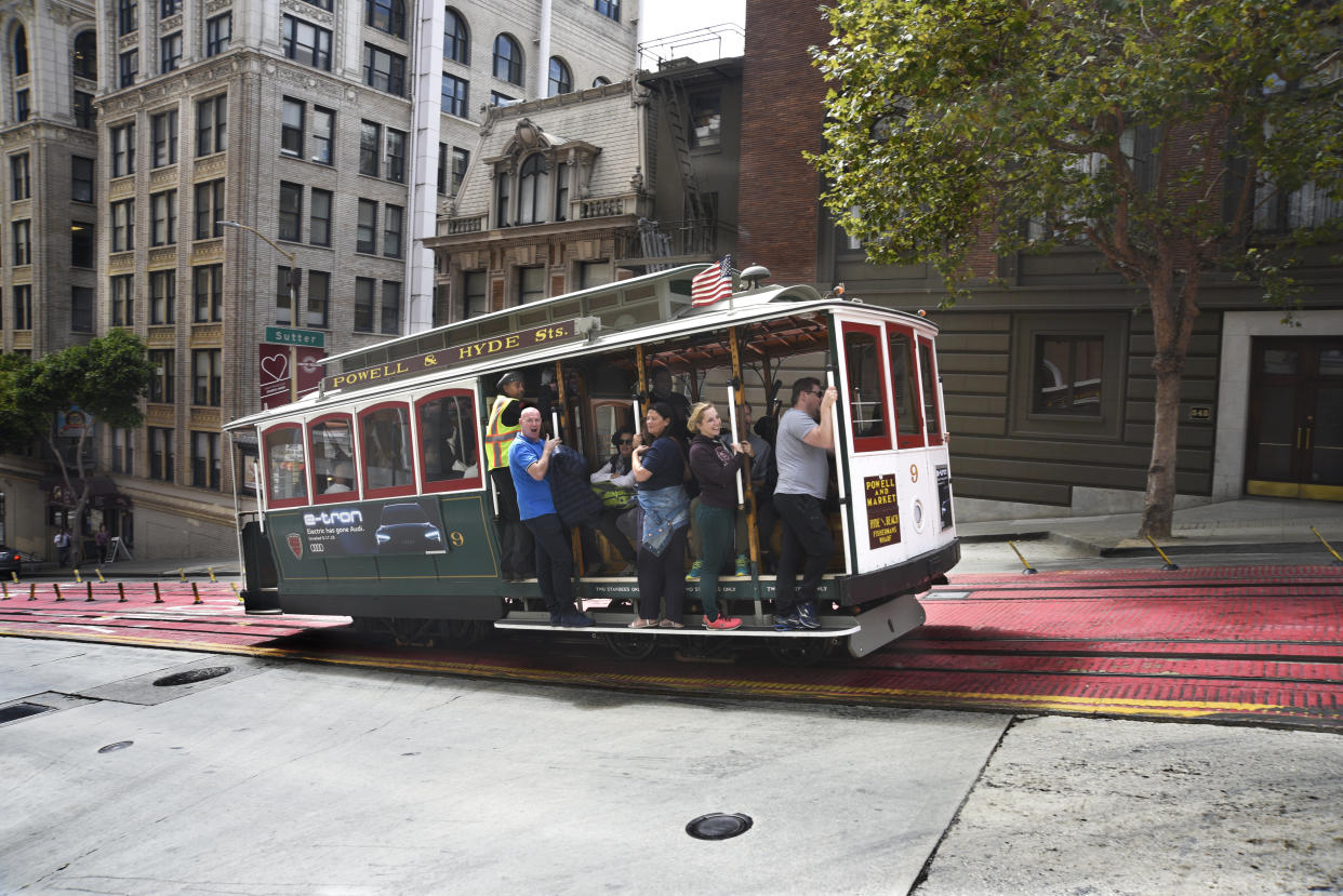 SAN FRANCISCO, CALIFORNIA - SEPTEMBER 14, 2018:  Tourists enjoy riding a cable car along Powell Avenue in San Francisco, California. (Photo by Robert Alexander/Getty Images)