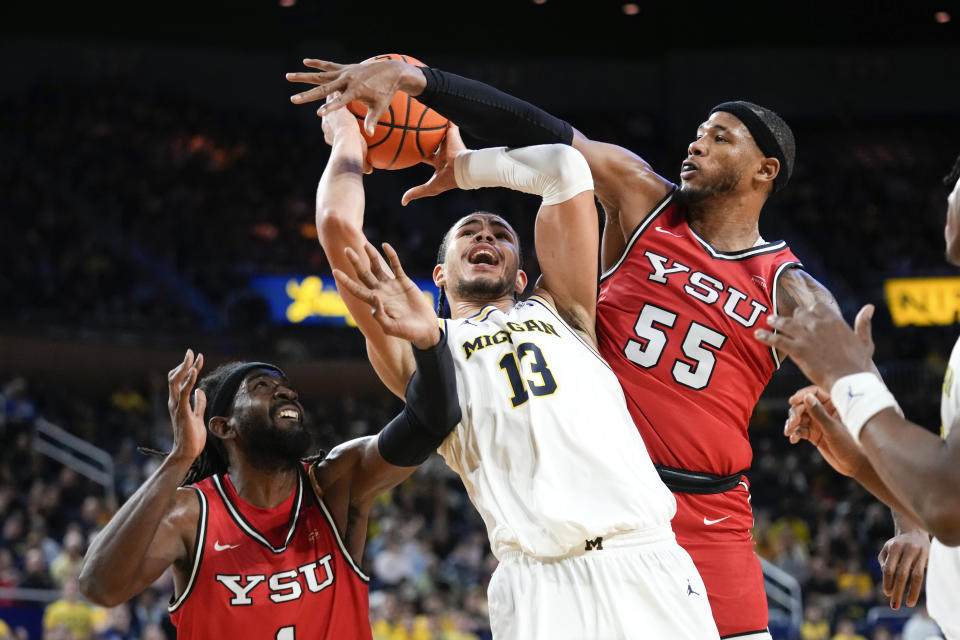 Michigan forward Olivier Nkamhoua (13) is fouled by Youngstown State forward DJ Burns (55) as Ziggy Reid, left, looks on in the second half of an NCAA college basketball game in Ann Arbor, Mich., Friday, Nov. 10, 2023. (AP Photo/Paul Sancya)