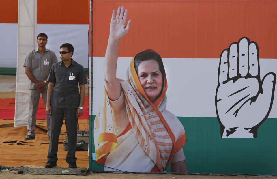 Indian security men stand guard near the cut out of Congress party president Sonia Gandhi during an election rally, in New Delhi, India,Sunday, April 6, 2014. (AP Photo /Manish Swarup)