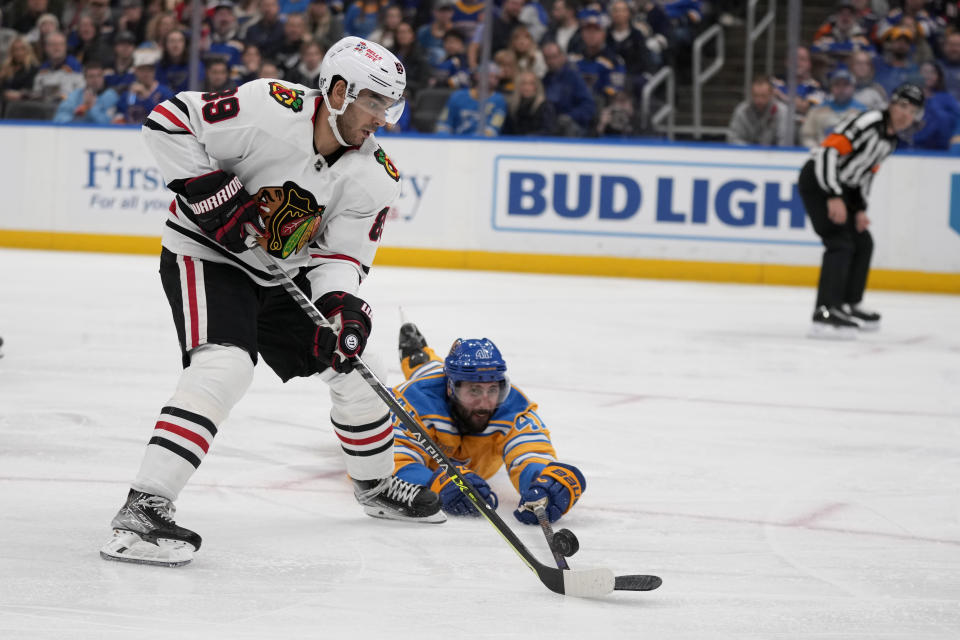 Chicago Blackhawks' Andreas Athanasiou (89) controls the puck as St. Louis Blues' Robert Bortuzzo defends during the third period of an NHL hockey game Thursday, Dec. 29, 2022, in St. Louis. (AP Photo/Jeff Roberson)