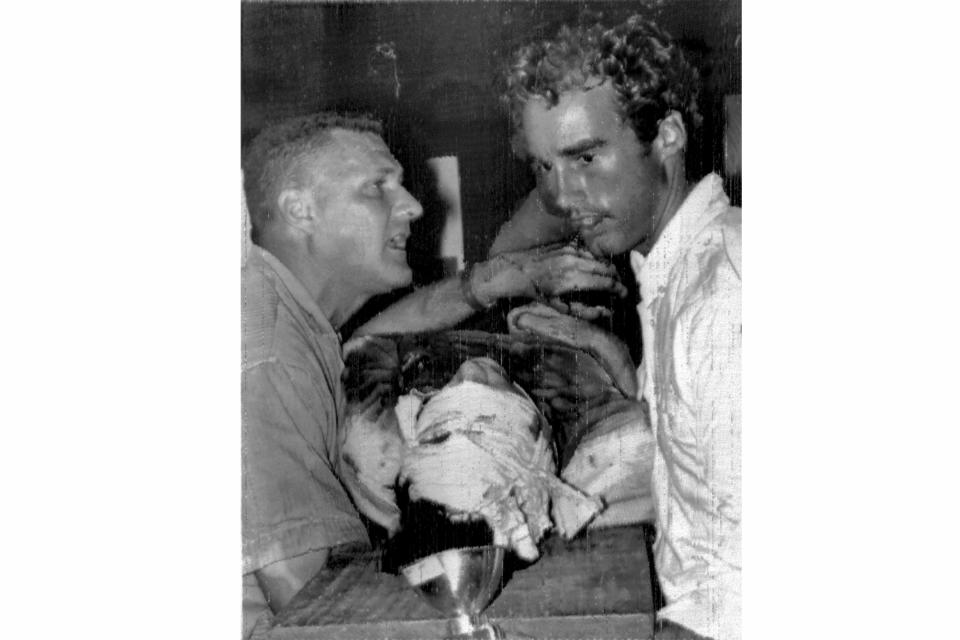 FILE - Wounded British photographer Tim Page lies on a board with his head bandaged as he is put on board an ambulance jeep in Da Nang, Vietnam, May 22, 1966, after he was hit by grenade fragments. Carrying him are Major Michael Styles of the U.S. Marines, left, and photographer Sean Flynn. Legendary Vietnam War photographer, writer and counter-culture documenter Tim Page died Wednesday, Aug. 24, 2022 at his Australian home. He was 78 years old. (AP Photo, File)