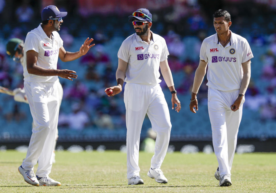 Indian bowlers Ravichandran Ashwin, left, Jasprit Bumrah and Navdeep Saini, right, talk during play on day three of the third cricket test between India and Australia at the Sydney Cricket Ground, Sydney, Australia, Saturday, Jan. 9, 2021. (AP Photo/Rick Rycroft)