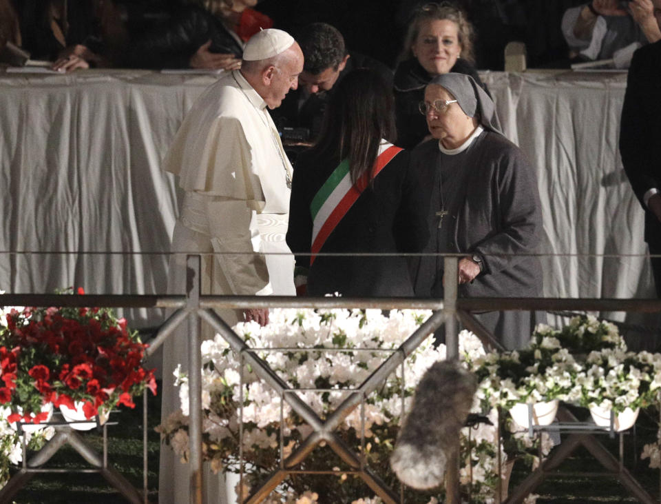 Pope Francis talks with Rome Mayor Virginia Raggi and Italian nun, Eugenia Bonetti, who composed this year's meditations, to be read aloud during the torchlight procession, during the Via Crucis (Way of the Cross) torchlight procession in front of Rome's Colosseum on Good Friday, a Christian holiday commemorating the crucifixion of Jesus Christ and his death at Calvary, in Rome, Friday, April 19, 2019. (AP Photo/Gregorio Borgia)