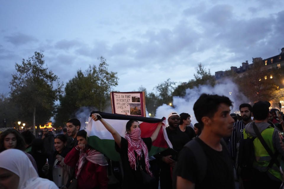 Protestors walk on the Republique square as riot police use tear gas during a rally in solidarity with the Palestinian people in Gaza, in Paris, Thursday, Oct.12, 2023. (AP Photo/Thibault Camus)