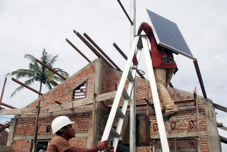 Indonesian workers install solar cell panels at Lam Awe district on the outskirts of Banda Aceh January 3, 2006. REUTERS/Tarmizy Harva/File Photo