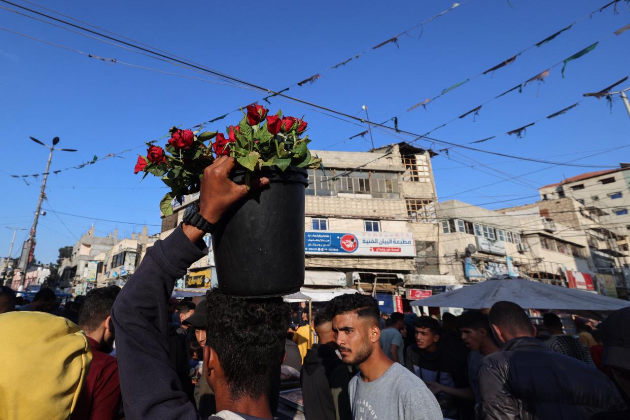 A Palestinian vendor carries a bucket with roses at an open market in Rafah in the southern Gaza Strip on April 9, 2024, ahead of Eid al-Fitr, which marks the end of the Muslim holy fasting month of Ramadan.
