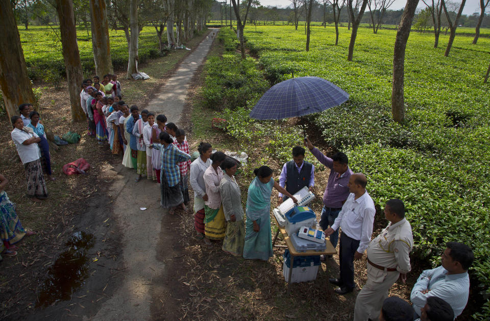 In this Monday, April 1, 2019, file photo, a woman casts her vote on the demo electronic voting machines and checks on Voter Verifiable Paper Audit Trail or VVPAT as others wait in the queue during an election awareness drive by district administration amongst the tea garden laborers ahead of India's general election in Jorhat, India. A VVPAT vending machine is an independent printing system connected to the electronic voting machines that allows voters to check that their votes are being cast as intended. The system will be used in the upcoming national elections to be held in seven phases starting from April 11. Votes will be counted on May 23. (AP Photo/Anupam Nath, File)