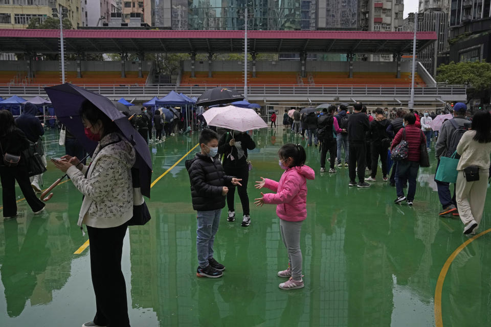 Children play as residents line up to get tested for coronavirus testing center in Hong Kong, Thursday, Feb. 17, 2022. Hong Kong on Thursday reported 6,116 new coronavirus infections, as the city’s hospitals reached 90% capacity and quarantine facilities are at their limit, authorities said. (AP Photo/Kin Cheung)