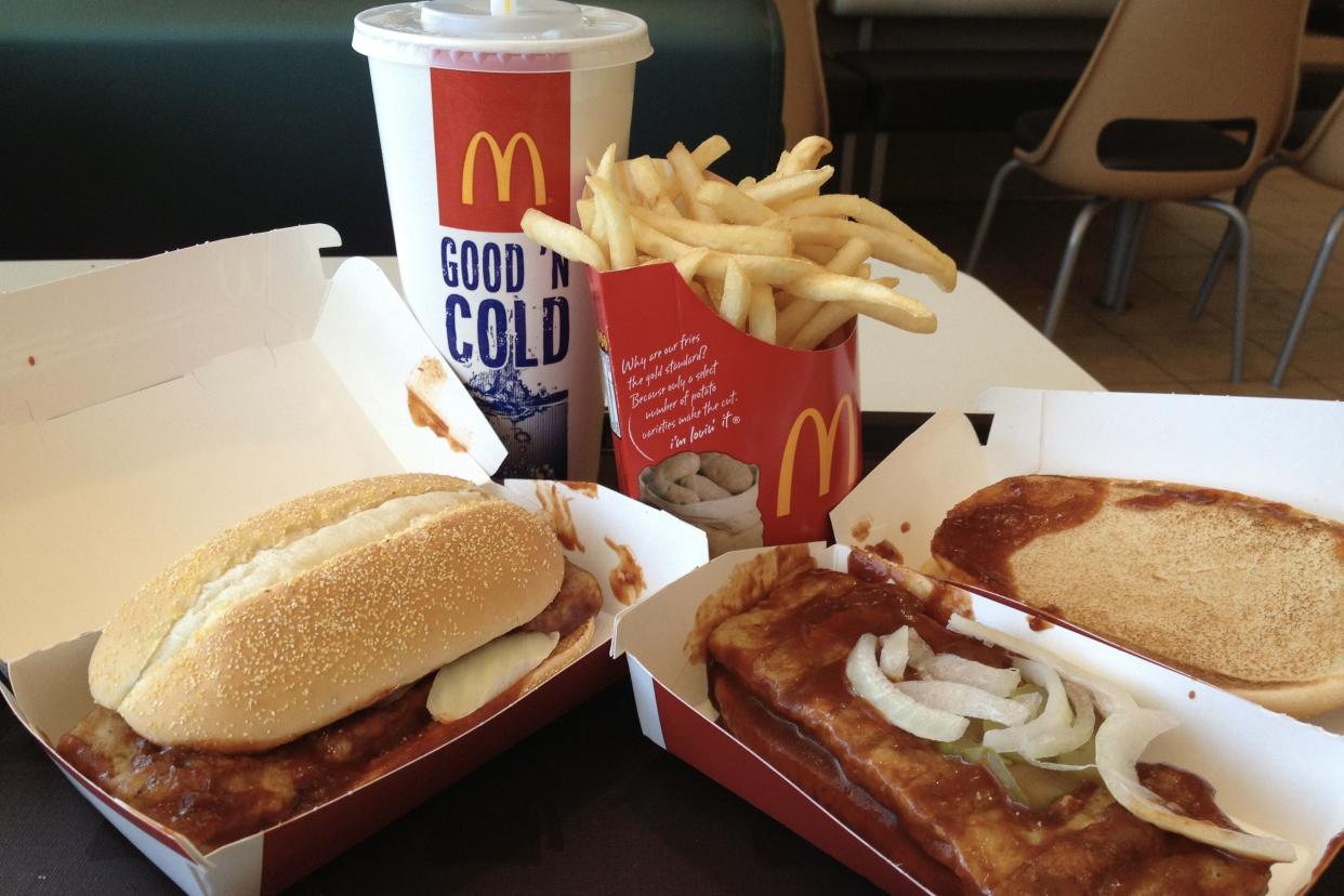 Two McDonald's McRib sandwiches with a soda and fries.