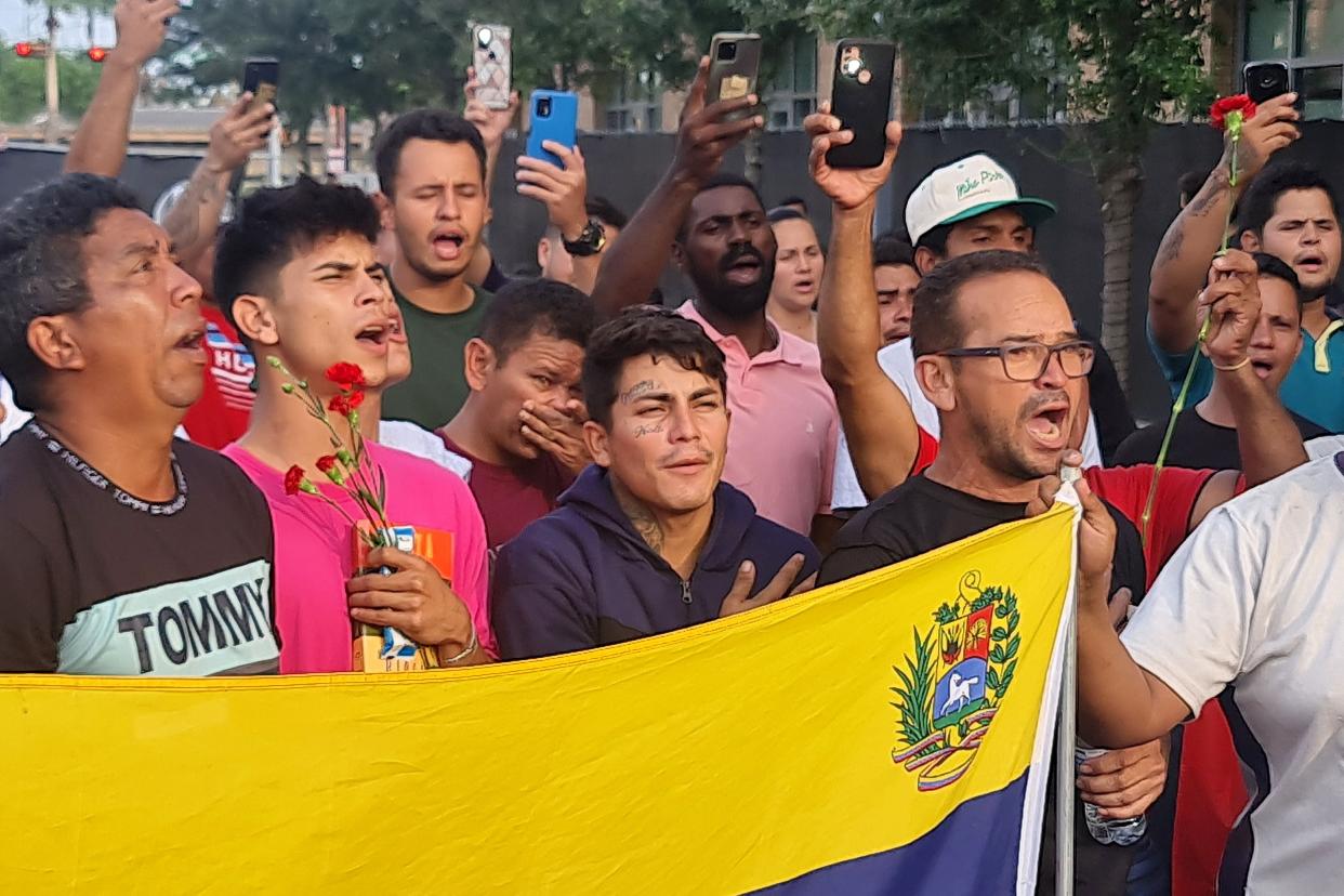 Venezuelan migrants chant and hold a Venezuelan national flag as they gather near The Plaza Bus Station, in Brownsville, Texas on 8 May 2023, a day after an SUV plowed into a crowd and killed eight (AFP via Getty Images)