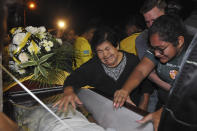 Relatives mourn over the coffin of a soccer fan killed in a bus crash at the Isidro Romero soccer stadium in Guayaquil, Ecuador, late Monday, Aug. 13, 2018. The bodies of 12 fans of Ecuadorean football team Barcelona that were killed when the bus they were traveling in after attending a local league match overturned were taken to the stadium for a collective funeral. (AP Photo/Jose Sanchez)