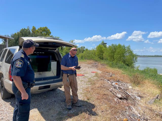 <p>St. Charles Parish Sheriff's Office</p> Authorities stand near vehicle