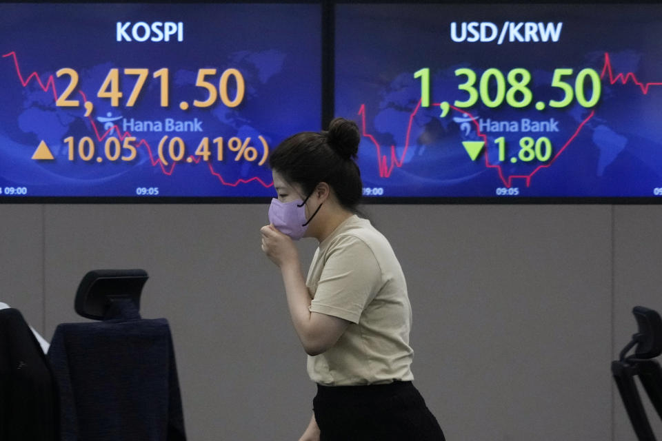 A currency trader passes by screens showing the Korea Composite Stock Price Index (KOSPI), left, and the exchange rate of South Korean won against the U.S. dollar at the foreign exchange dealing room of the KEB Hana Bank headquarters in Seoul, South Korea, Thursday, Aug. 4, 2022. Asian shares mostly rose Thursday as investors welcomed encouraging economic data and quarterly earnings reports from big companies. (AP Photo/Ahn Young-joon)