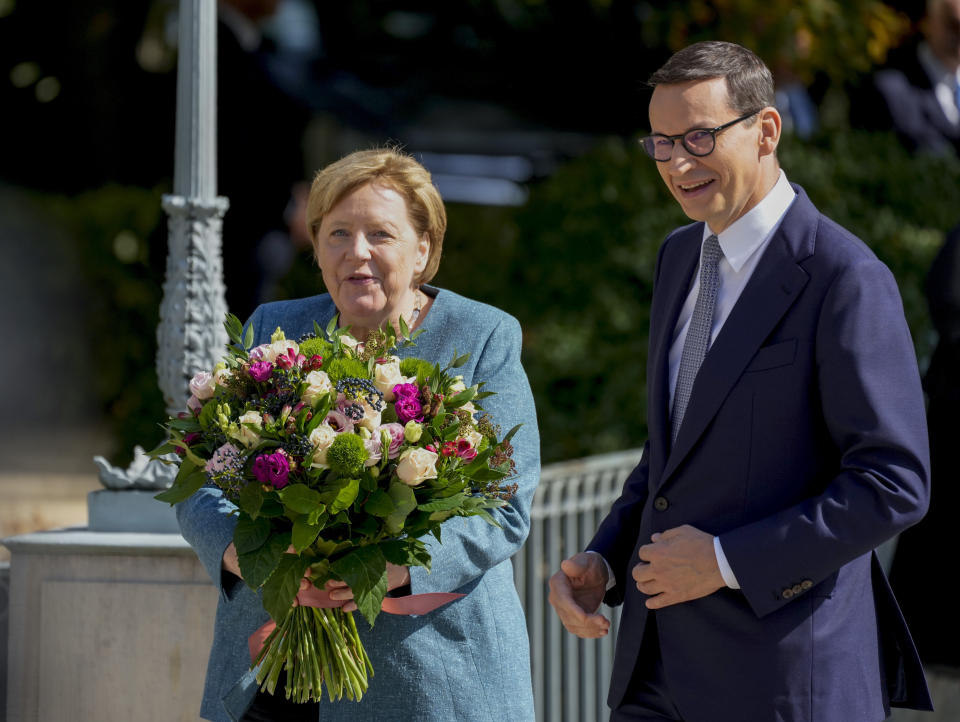 German Chancellor Angela Merkel holds flowers as she meets Poland's Prime Minister Mateusz Morawiecki in Warsaw, Poland, Saturday, Sept.11, 2021.Merkel is visiting the Polish capital Morawiecki at a time when Poland faces migration pressure on its eastern border with Belarus. (AP Photo/Czarek Sokolowski)