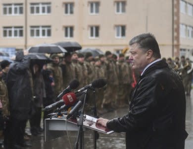 Ukrainian President Petro Poroshenko (R) delivers a speech in the rain during the ceremony of presenting new apartment certificates to local residents, including servicemen of the Ukrainian armed forces, during his working trip to Dnipropetrovsk region, Ukraine November 20, 2017. Mykola Lazarenko/Ukrainian Presidential Press Service/Handout via REUTERS