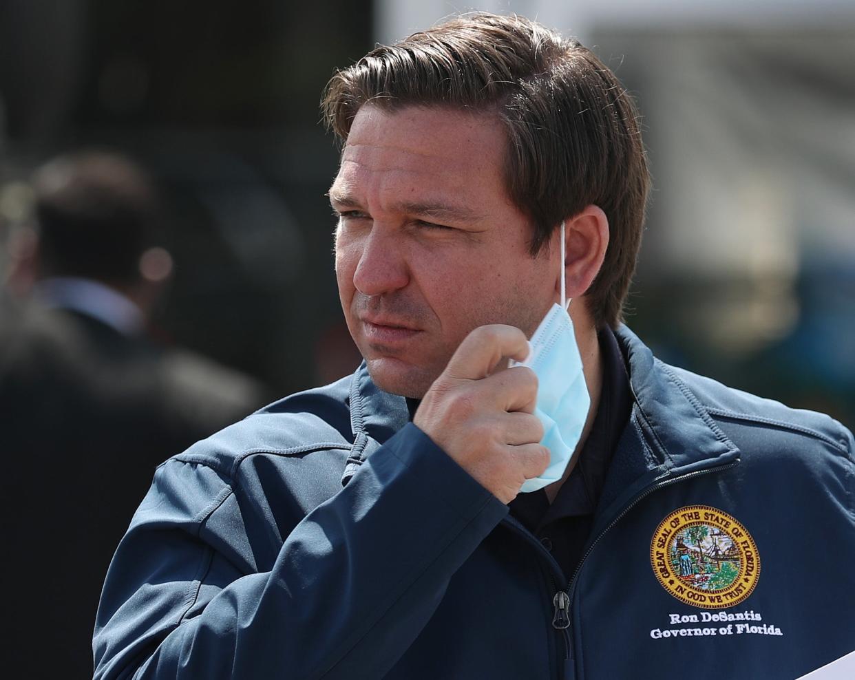 <p> Florida Gov. Ron DeSantis takes his mask off as he prepares to speak during a press conference at the Hard Rock Stadium testing site on May 06, 2020 in Miami Gardens, Florida. </p> ((Photo by Joe Raedle/Getty Images))