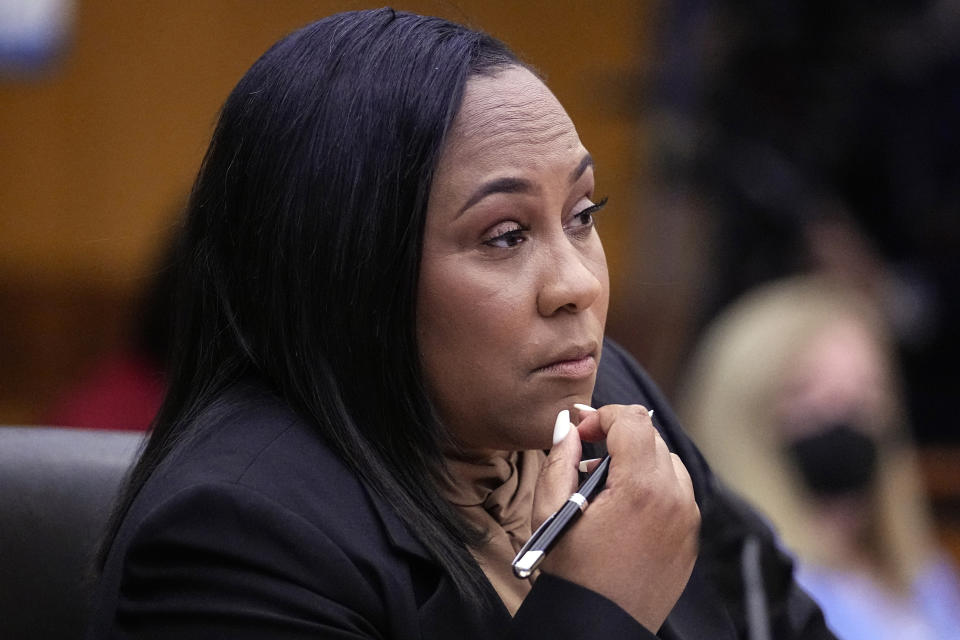 Fulton County District Attorney Fani Willis listens in court, holding a pen. 