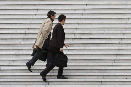 Businessmen carry briefcases as they climb the stairs under the Arche de la Defense in the financial and business district west of Paris October 21, 2014. REUTERS/John Schults