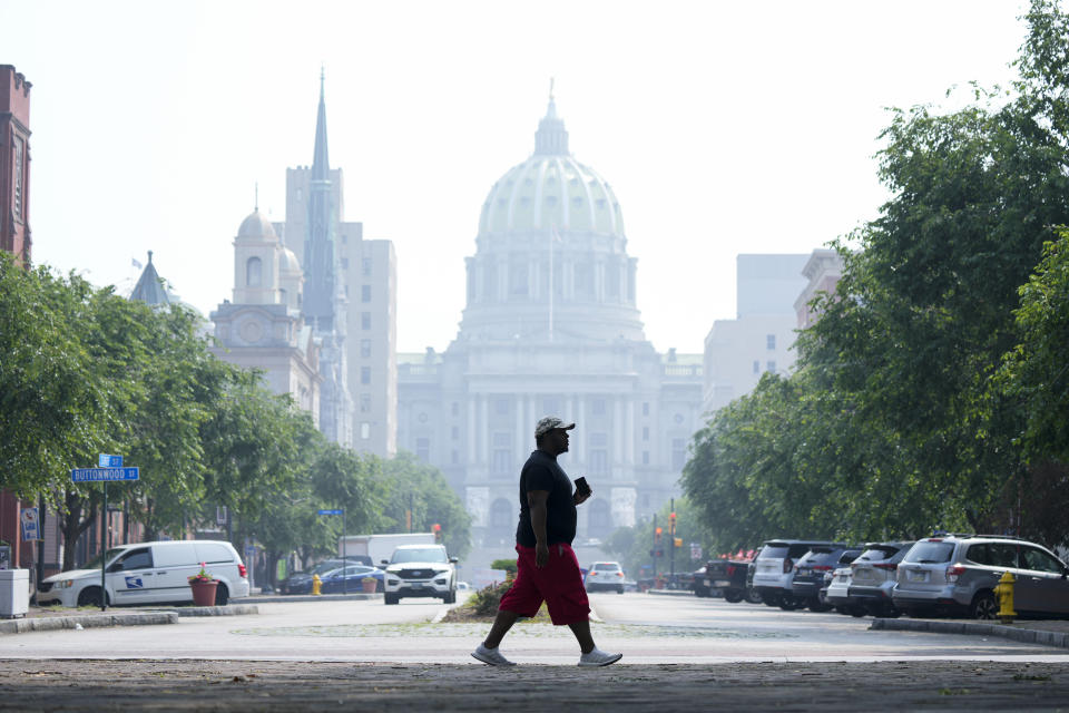 A person walks by the state Capitol in Harrisburg, Pa., shrouded in haze from Canadian wildfires on Thursday, June 29, 2023. (AP Photo/Matt Rourke)