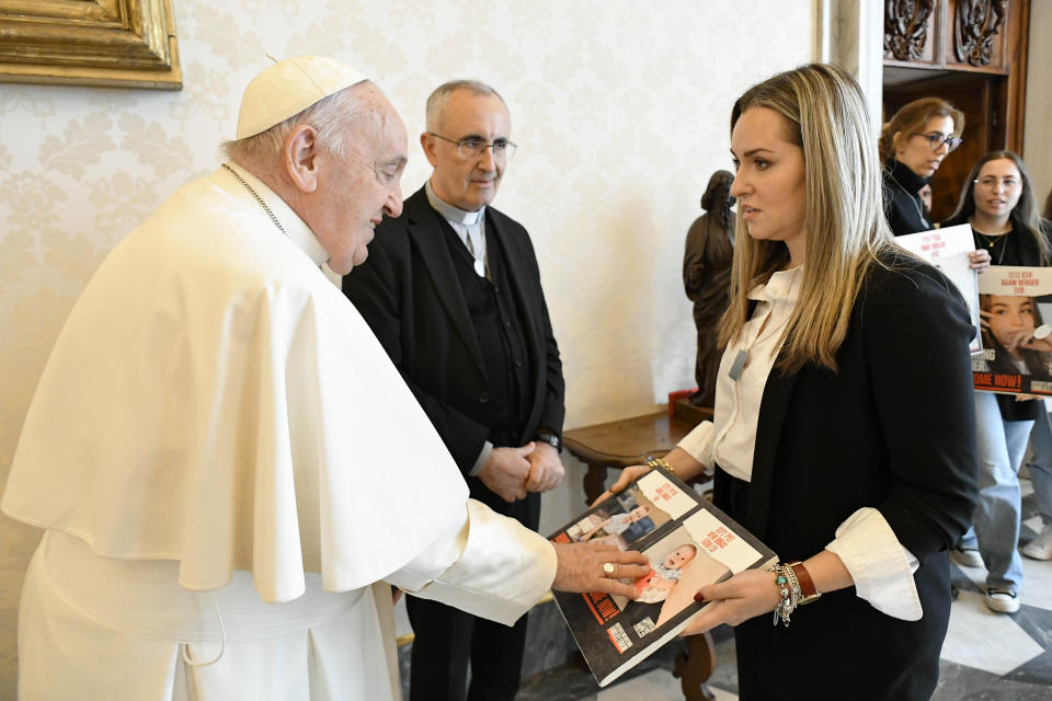 Pope Francis touches a photograph of a child as he meets with Ashley Waxman Bakshi, right, and other relatives of Israeli hostages being held by Hamas, at the Vatican, Monday, April 8, 2024. Israel sent troops to Khan Younis in December, part of its blistering ground offensive that came in response to a Hamas-led attack on Oct. 7 into southern Israel. Israeli authorities say 1,200 people, mostly civilians, were killed and roughly 250 people taken hostage. (Vatican Media via AP)