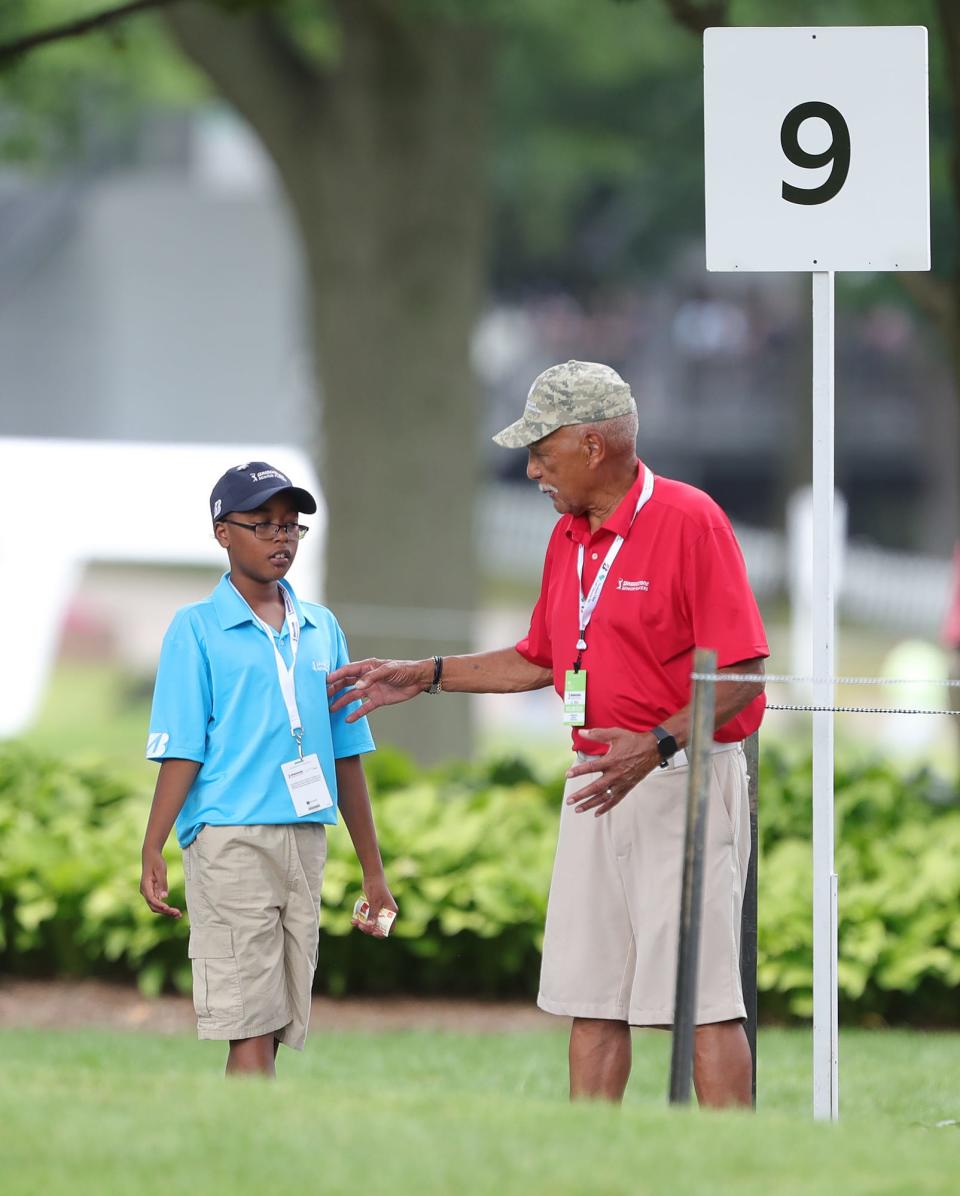 Volunteer Les Carney, right, chats with his grandson Issa Perry, 9, of Kent, as they work path between holes 9 and 10 during second round of the 2024 Bridgestone Senior Players Tournament at Firestone Country Club on July 10.