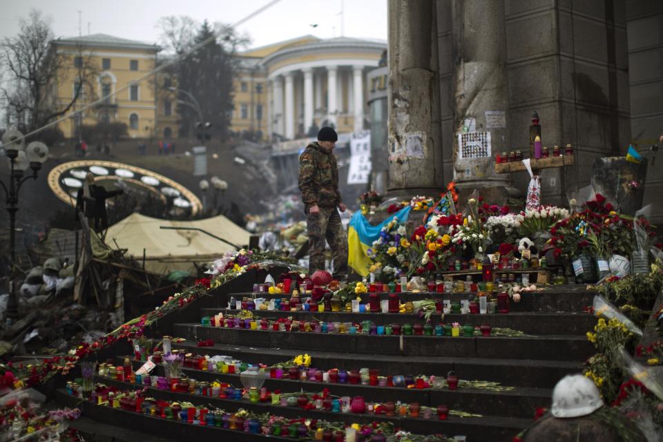 An anti-Yanukovych protester stands at a memorial for the people killed in clashes with the police at Kiev's Independence Square, the epicenter of the country's current unrest, Saturday, March 1, 2014. The pro-Russian prime minister of Ukraine's restive Crimea is claiming control of all military forces, police and other security services in the region. In a statement reported by local and Russian news agencies on Saturday, Sergei Aksenov declares that the armed forces, the police, the national security service and border guards will answer only to his orders. He says that any commanders who don't agree should leave their posts. (AP Photo/Emilio Morenatti)