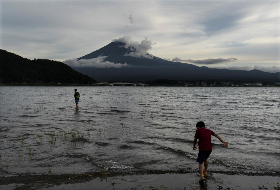 A boy walks into the water Tuesday, Aug. 6, 2019, in Lake Kawaguchi with Mount Fuji in the background, west of Tokyo. (AP Photo/Jae C. Hong)