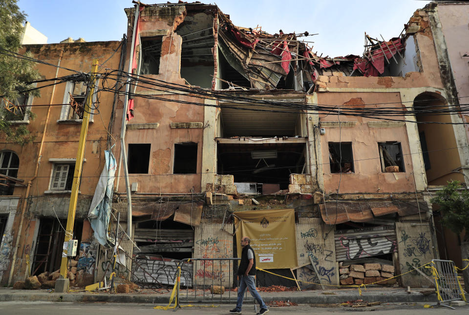 A man passes by a historical building that was damaged by the August 2020 massive explosion at th seaport, in Beirut, Lebanon, Tuesday, Feb. 2, 2021. The blast was one of the largest non-nuclear explosions in history and six months later, political and confessional rivalries have undermined the probe into the Beirut port explosion and brought it to a virtual halt, mirroring the same rivalries that have thwarted past attempts to investigate political crimes throughout Lebanon's history. (AP Photo/Hussein Malla)