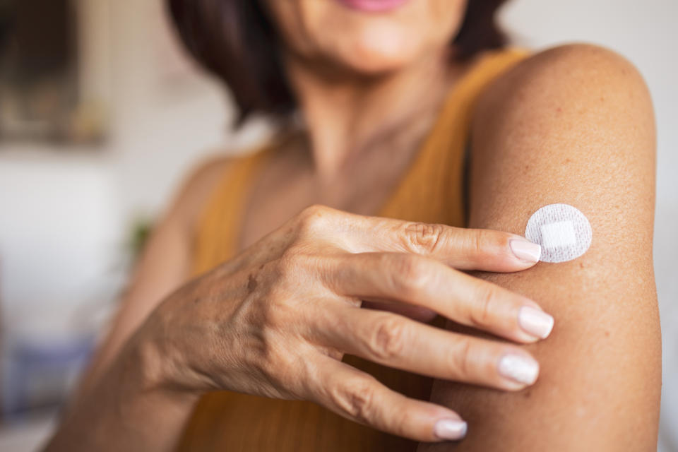 Woman sticking a hormone replacement patch to her upper arm