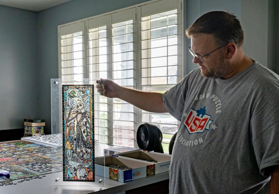 John Walczak shows some of his huge collection of jigsaw puzzles Friday, May 3, 2024 in his Carmel home. This “Nightmare Before Christmas” puzzle was the first one he did with his wife, Kyle. He recently achieved a Guinness World Record for the largest collection of jigsaw puzzles.