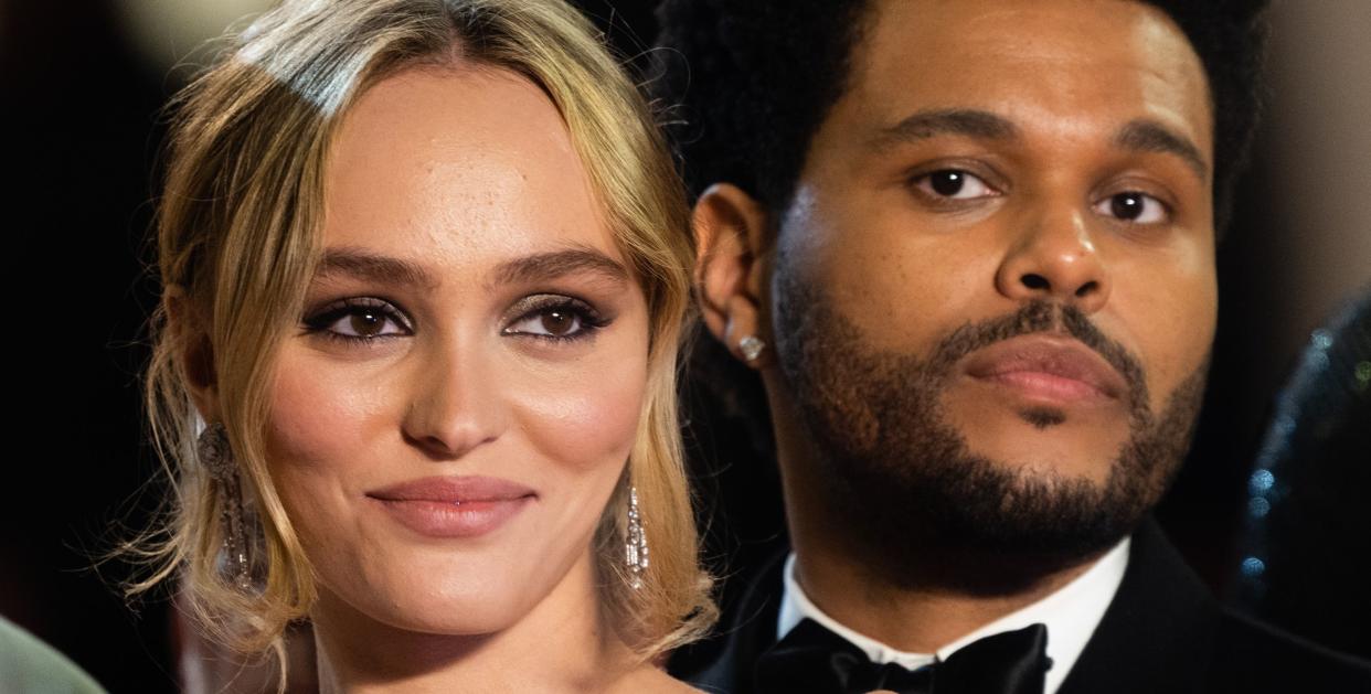 lily rose depp, wearing a green dress, and the weeknd, wearing a black tuxedo, smiling for the camera