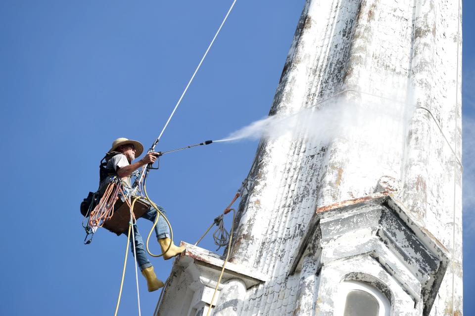 Steeplejack Fred Franklin pressure washes the steeple at First Christian Church.