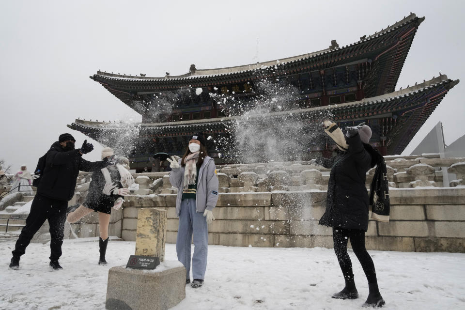 Visitors toss snow to enhance their pictures at the Gyeongbok Palace, the main royal palace during the Joseon Dynasty, and one of South Korea's well known landmarks in Seoul, South Korea, Thursday, Jan. 26, 2023. (AP Photo/Ahn Young-joon)