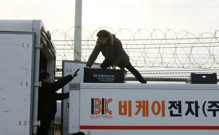 South Korean workers transfer packs from a vehicle after leaving the Kaesong joint industrial zone, outside a military checkpoint in Paju on February 11, 2016