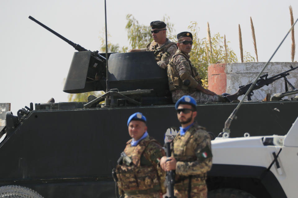 Italian U.N. peacekeepers stand next of Lebanese soldiers who sit on their armored personal carrier, on a road that leads to a U.N. post along the border known as Ras Naqoura where Lebanese and Israeli delegations are going to meet, in Naqoura, Lebanon, Thursday, Oct. 27, 2022. Lebanon signed and delivered its copy of a U.S.-mediated sea border deal with Israel on Thursday to a U.S. mediator, hoping to soon start exploring gas in its southern maritime blocs to bring economic stability to the crisis-ridden country. (AP Photo/Mohammed Zaatari)