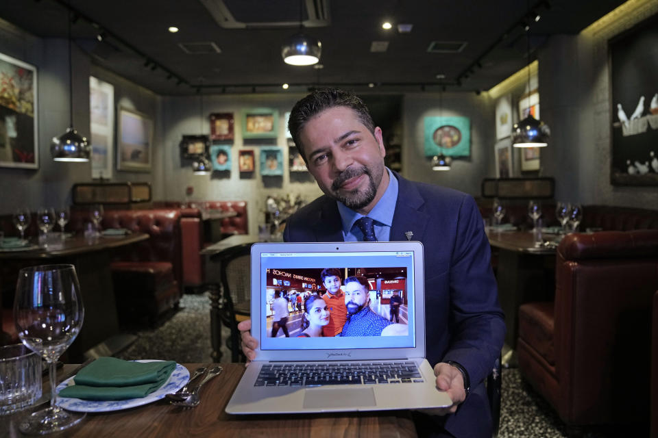 Sandeep Arora from Punjab, India, a restaurant manager at Black Sheep's New Punjab Club, shows his family photo with wife and son during an interview in Hong Kong on Nov. 26, 2021. The bustling, cosmopolitan business hub of Hong Kong may be losing its shine among foreign companies and expatriates with its stringent anti-pandemic rules requiring up to 21 days of quarantine for new arrivals. (AP Photo/Kin Cheung)