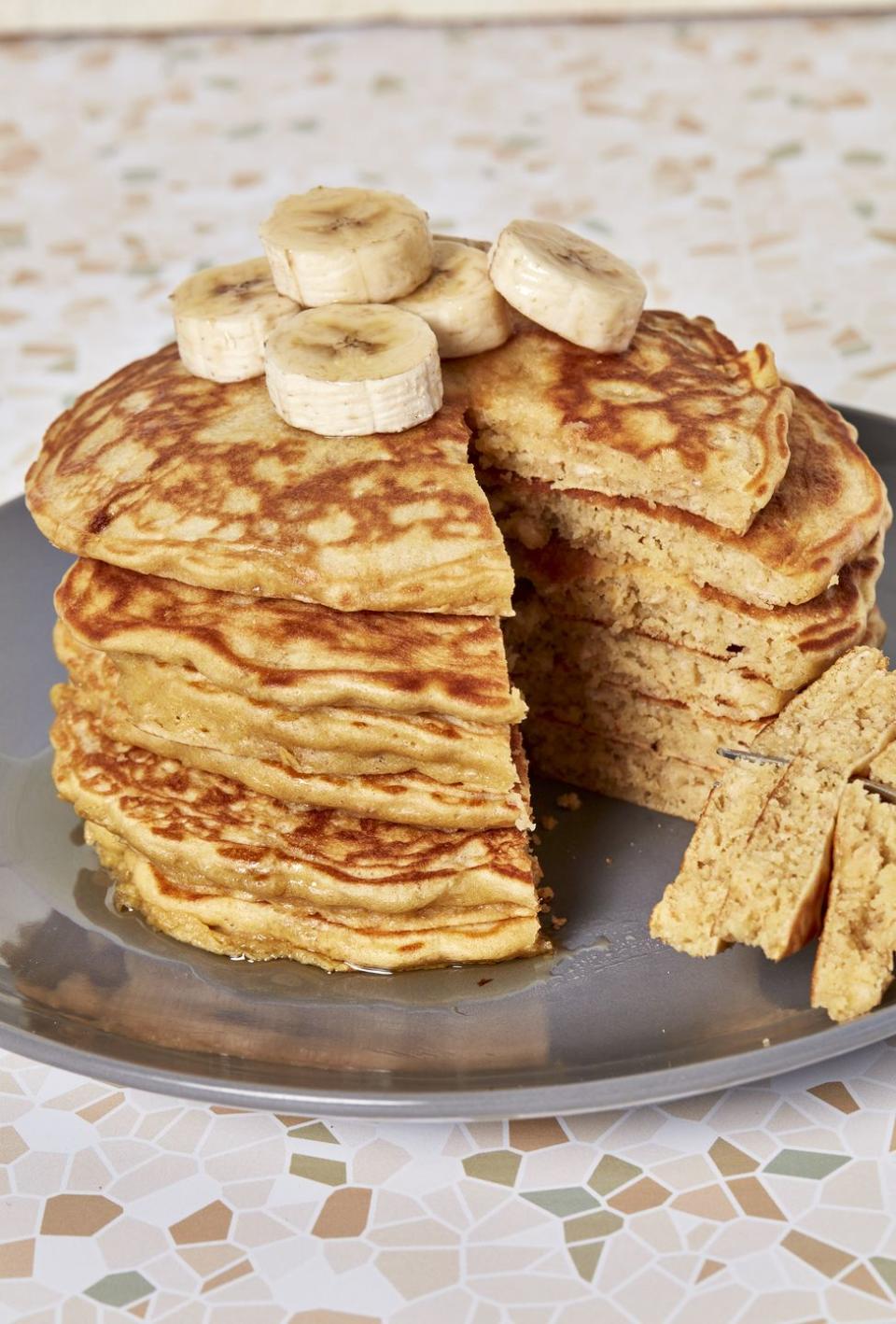 stack of oatmeal pancakes topped with banana on a plate