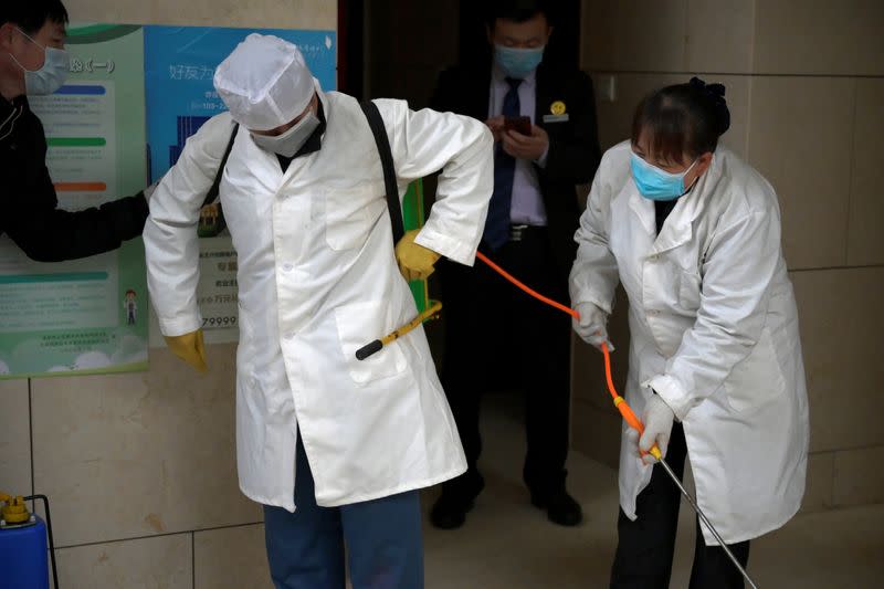 Worker Gong Lixia helps her colleague Wang Fu to put on the disinfectant liquid backpack as they sanitise a residential compound, following an outbreak of the novel coronavirus in the country, in Beijing