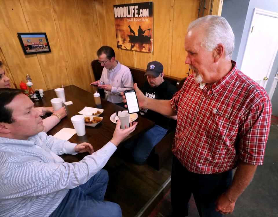 Chad White, left, shows Joe Carr, right the election results  for the Rutherford County Mayor's race on a cell phone during Carr's election result party at Slick Pig BBQ on Tuesday, May 3, 2022. It was later announced that Carr unseated Bill Ketron as Rutherford County Mayor. 