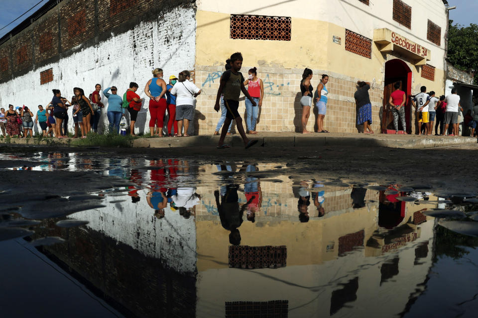 FILE - In this Tuesday, March 31, 2020 file photo, neighbors line up for free food staples outside Santa Ana primary school in Asuncion, Paraguay, part of an already existing food program through the Education Ministry, as people stay home from work amid the spread of the COVID-19 coronavirus. According to research released on Wednesday, April 1, 2020, more evidence is emerging that coronavirus infections are being spread by people who have no clear symptoms, complicating efforts to gain control of the pandemic. (AP Photo/Jorge Saenz)