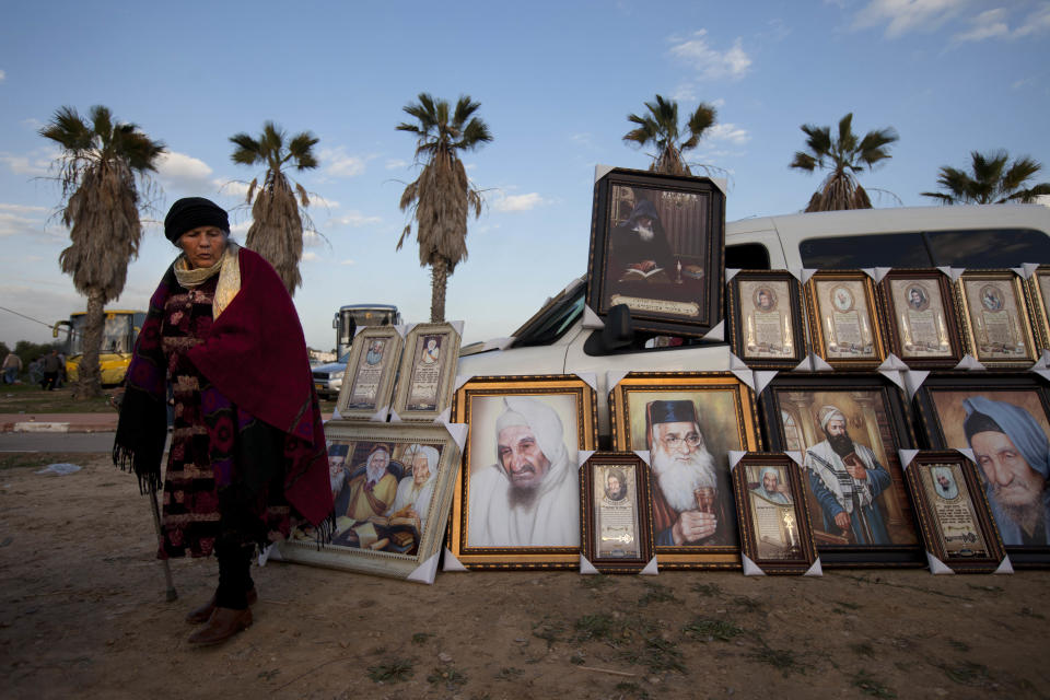 FILE -In a Thursday Jan. 26, 2012 file photo a Jewish woman stands next to pictures of rabbis for sale near the tomb of the Baba Sali, Rabbi Yisrael Abuhatzeira, during the annual pilgrimage to his grave on the 28th anniversary of his death, in the southern Israeli town of Netivot. Over the past few decades, dozens of rabbis have carefully positioned themselves at the fulcrum of Israeli power and influence. (AP Photo/Oded Balilty, File)